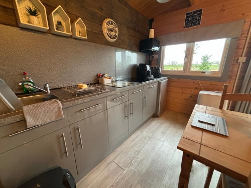 a kitchen with white cabinets and a sink and a table at Rife Lodges in Arundel