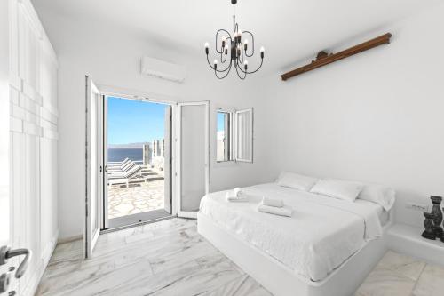 a white bedroom with a bed and a large window at MichaelAngelo Villa in Mikonos