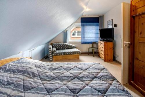 1 dormitorio con cama, sofá y TV en Das Ferienhaus Schöne Lizzy befindet sich in Neßmersiel und ist die ideale Unterkunft für einen erholsamen Urlaub, en Nessmersiel