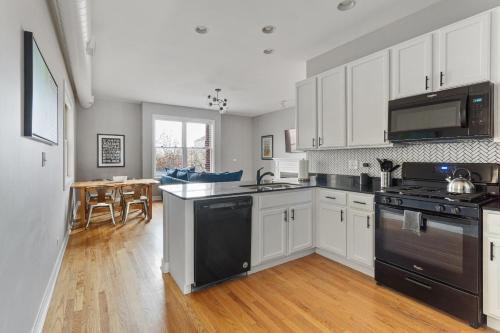 a kitchen with white cabinets and black appliances at The Upscale Getaway Near Downtown in Chicago