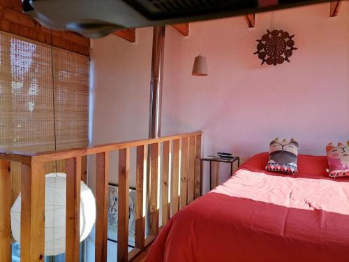Un dormitorio con una cama roja con dos zapatos. en Home Loft Pichilemu, en Pichilemu