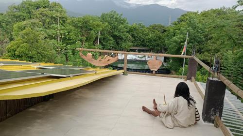 a woman sitting on a bridge with two people swinging at Bio Coliving Tayrona in Santa Marta
