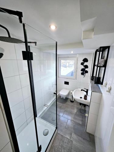 a white bathroom with a shower and a sink at Pohl Fewo in Remscheid