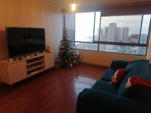 Sala de estar con árbol de Navidad y TV en departamento frente al mar playa brava, en Iquique