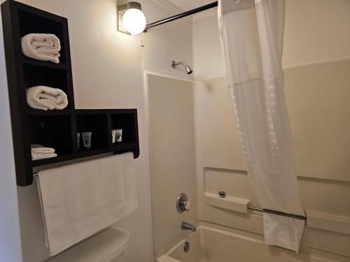 a bathroom with a shower and a toilet and towels at Astoria Hotel West in Danville