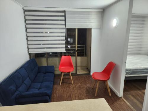 a living room with a couch and two red chairs at Vivaceta Metro Hospitales in Santiago