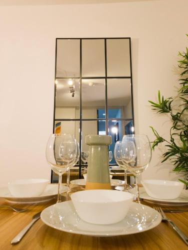 a table with wine glasses and a mirror at Plenty of Parking Available; 3 Bedroom Apartment by Property Promise in Cardiff