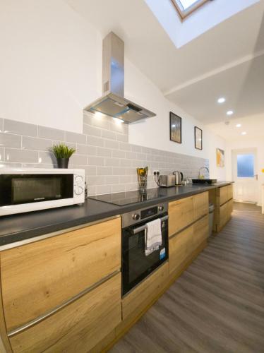 a kitchen with a stove and a microwave at Plenty of Parking Available; 3 Bedroom Apartment by Property Promise in Cardiff