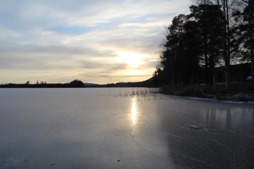 a large body of water with the sun setting in the background at Fristad Nature House in Torsby