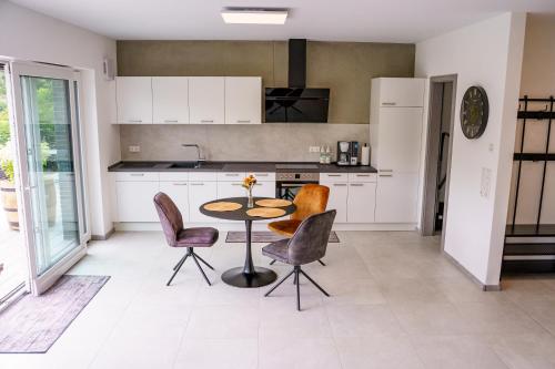 a kitchen with white cabinets and a table and chairs at MV Römervilla, Lofts & Penthouses mit traumhaftem Moselpanoramablick und Sauna in Treis-Karden