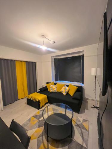 a living room with a black couch and yellow pillows at Sleek Cosy Flat Camden in London
