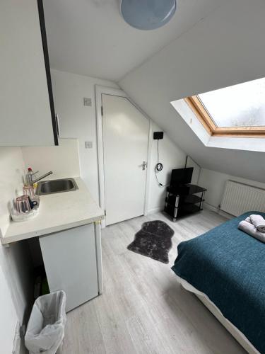 a bedroom with a bed and a sink and a kitchen at Cozy Urban Terraced Studio in London