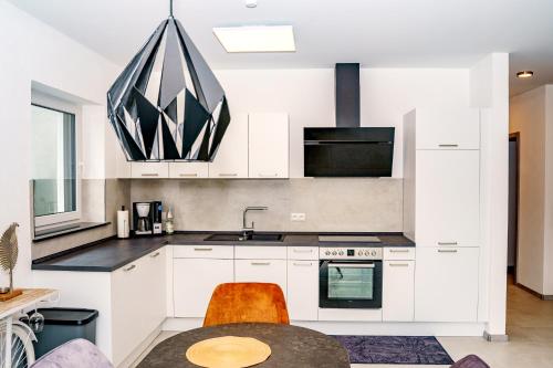 a kitchen with white cabinets and a sink and a table at MV Römervilla, Lofts & Penthouses mit traumhaftem Moselpanoramablick und Sauna in Treis-Karden