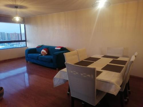 sala de estar con mesa y sofá azul en departamento frente al mar playa brava, en Iquique