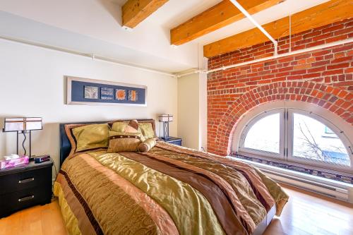 1 dormitorio con cama y pared de ladrillo en Les Lofts 1048, en Quebec