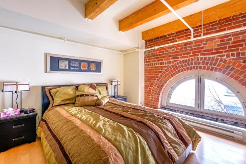 een slaapkamer met een bed en een bakstenen muur bij Les Lofts 1048 in Québec