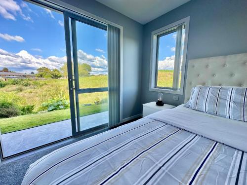 una camera con un letto e una grande finestra di Maple Retreat by Blue Spring a Putaruru