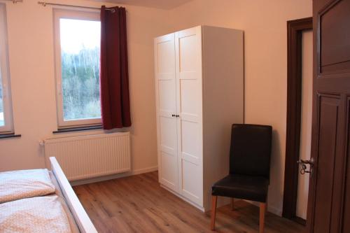 a bedroom with a white cabinet and a black chair at Harzhaus Drei Hexen in Tanne
