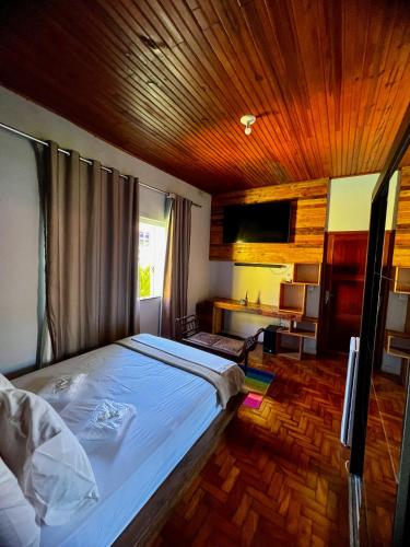 a bedroom with a large bed with a wooden ceiling at HOSTEL BADULACK in Capitólio