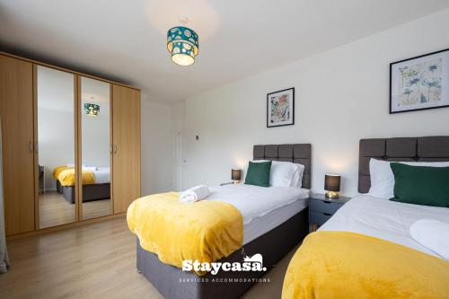 a bedroom with two beds and a mirror at Spacious Cosy Cove With Large Driveway And Garden in Wythenshawe