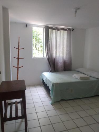 1 dormitorio con cama, ventana y mesa en Quarto Casal privativo em apartamento, en Salvador
