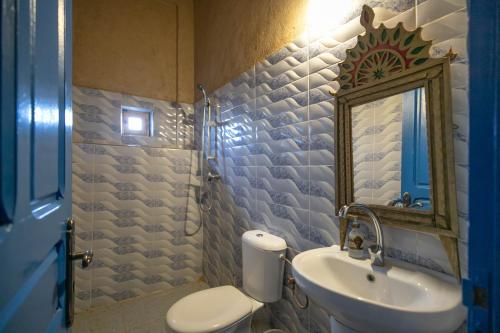 a bathroom with a sink and a toilet and a mirror at Dar Duna in Adrouine
