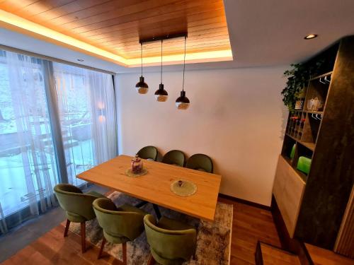 a dining room with a wooden table and green chairs at Drop Kop in Brzeće