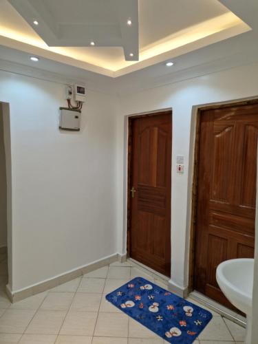 La salle de bains est pourvue d'un lavabo, d'une porte et d'un tapis. dans l'établissement Savanna Greens Joska, à Nguluni