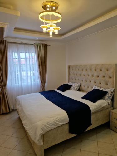 a bedroom with a large bed and a chandelier at Savanna Greens Joska in Nguluni