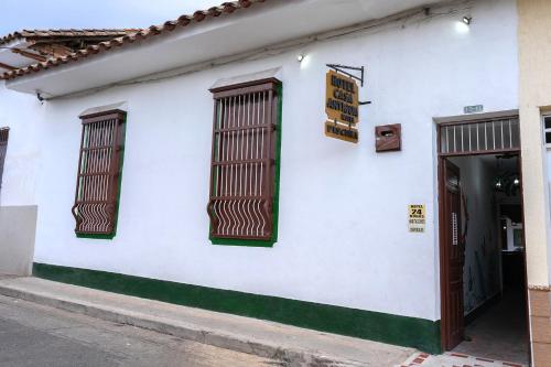 a white building with two windows and a door at Hotel Casa Antigua Buga in Buga