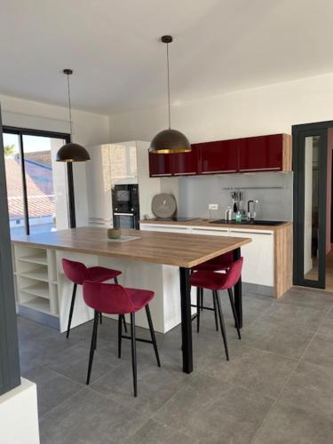 une cuisine avec une table en bois et des chaises rouges dans l'établissement Maison entre port et plage, à Mèze
