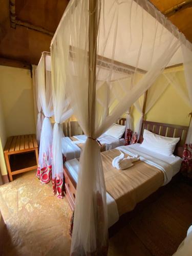 a bedroom with two beds with mosquito netting at Patamu Restaurant & Lodge in Karatu