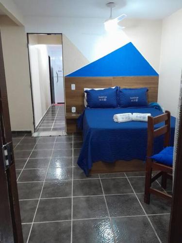 a bedroom with a blue bed and a chair at Aconchego da Gil in Rio das Ostras