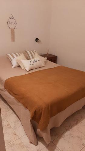 Una cama con una manta marrón encima. en Ruka Leufu en Santa Rosa de Calamuchita