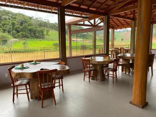 a dining room with tables and chairs and windows at Pousada Rural Recanto do Lago in Pedra Azul