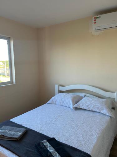 um quarto com uma cama branca e uma janela em Agapanto Praia em Marechal Deodoro