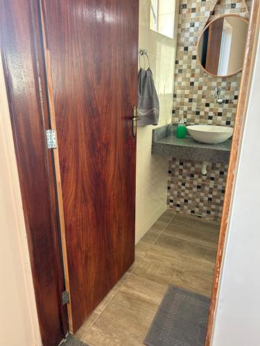 uma casa de banho com uma porta de madeira e um lavatório em Agapanto Praia em Marechal Deodoro