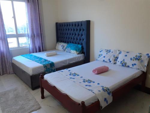 een slaapkamer met 2 bedden en een raam bij TWO BEDROOM APARTMENT BAMBURI Mombasa in Mombasa