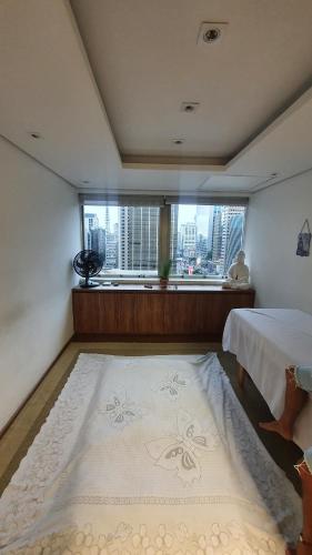 een slaapkamer met een bed en een groot raam bij Estudio Avenida Paulista in Sao Paulo