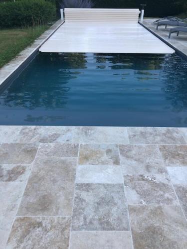 un bassin d'eau avec un banc à côté dans l'établissement agréable chambre d hôte avec piscine et jacuzzi, à Thégra