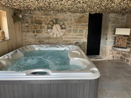 a jacuzzi tub in a room with a clock at agréable chambre d hôte avec piscine et jacuzzi in Thégra
