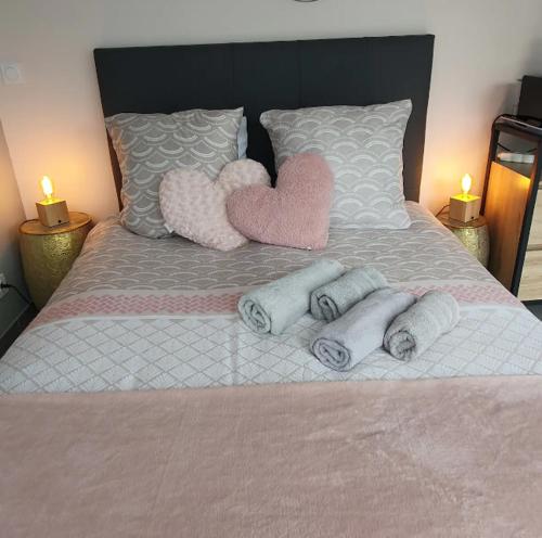a bed with two hearts and towels on it at Cottage de la mare aux chèvres in Reux