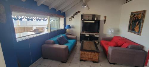 a living room with two couches and a tv at Sublime appartement face à la mer, vue panoramique in Saint-François