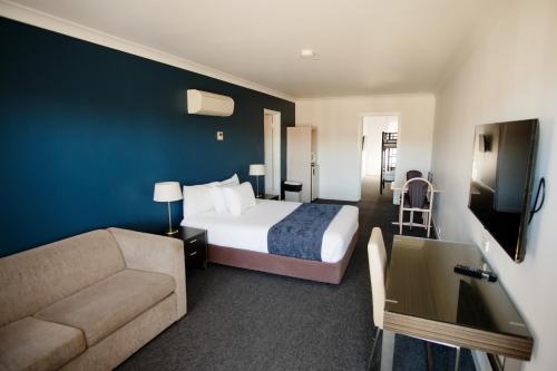 um quarto de hotel com uma cama e um sofá em Golden Age Motor Inn em Queanbeyan