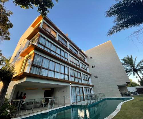 a building with a swimming pool in front of it at Guarajuba Suítes Premium Boutique Hotel in Guarajuba