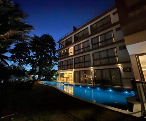 a building with a swimming pool at night at Guarajuba Suítes Premium Boutique Hotel in Guarajuba