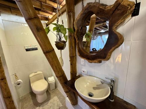 a bathroom with a sink and a mirror and a toilet at Bella Flor Hostel Palomino in Palomino