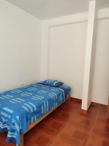 Schlafzimmer mit einem Bett mit blauer Bettwäsche und Holzboden in der Unterkunft Mini departamentos in Camaná