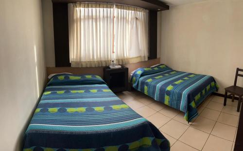 1 dormitorio con 2 camas y ventana en Hostal Marbella, en Camaná