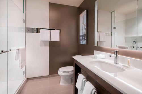 a bathroom with a sink and a toilet and a mirror at Residence Inn by Marriott Redwood City San Carlos in San Carlos